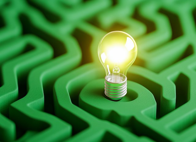 Leuchtende Glühbirne steht in der Mitte eines grünen Labyrinths aus Kunststoff oder Gummi – Symbol für eine Idee oder Lösung innerhalb einer komplexen Struktur.