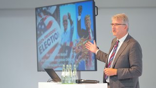 Bild von der Bühne und vom Keynotespeaker des IHK-Strategieforums 2024 mit dem Schwerpunkt USA.