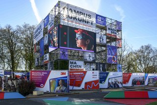 Campus Zukunft: Außenansicht eines mehrstöckigen, Gerüstes mit großflächigen Informations- und Motivtafeln zum Thema Innovation, Wissenschaft und Wirtschaft.