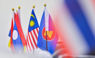 Nationalflaggen von Laos, Malaysia und der ASEAN in einer Reihe, scharf im Vordergrund, mit unscharfem Hintergrund.