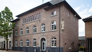 Das Bild zeigt das Rathaus in Schwalmtal, ein Backsteingebäude mit hellen Fensterrahmen und einem klassischen, symmetrischen Fassadenaufbau. 