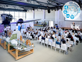 Das Bild zeigt das Publikum und den Keynote-Speaker des IHK-Forum Zoll 2026 im Hugo Junkers Hangar in Mönchengladbach.