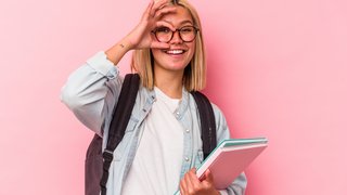 Junge Auszubildende mit Briller vor rosa Wand mit Rucksack und Ordner