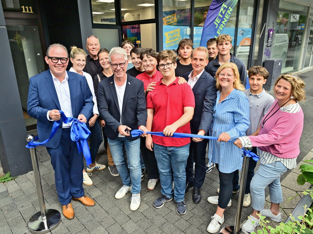 Hauptgeschäftsführer Jürgen Steinmetz (vorne, 2.v.l.) hat gemeinsam Schülerinnen und Schülern der Gesamtschule Uerdingen, dem gesamten Orga-Team um IHK-Geschäftsführerin Daniela Perner (3.v.r.) und vielen Gästen mit dem Durchschneiden des Bandes symbolisch den Pop-Up-Store Ausbildung eröffnet. 