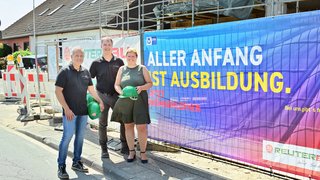 Mit der Werbebanner-Kampagne unterstützt die IHK Unternehmen und insbesondere Ausbildungsbetriebe dabei, auf ihre Ausbildungsangebote aufmerksam zu machen. Im Falle der Reuter Bauunternehmen GmbH ist das Banner an einem Bauzaun befestigt worden –  im Beisein von Geschäftsführer Mario Prömpers (l.), dem technischen Leiter Bernd Wirtz und IHK-Geschäftsführerin Daniela Perner.