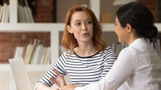 Multiracial female colleagues brainstorm ideas using laptop