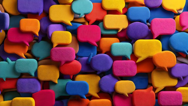 Viele bunte, sich überlappende Sprechblasen in kräftigen Farben wie Rot, Blau, Gelb, Orange, Pink, Lila und Türkis, aufeinander gestapelt und texturiert, ohne sichtbaren Text oder Symbole.