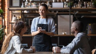 Smiling waitress taking order from multiracial clients