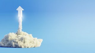 Grafik einer weißen Rakete in Form eines Pfeils, die senkrecht nach oben startet. Die Rakete hebt aus einer dichten weißen Rauchwolke ab und hinterlässt eine leuchtende Spur. Der Hintergrund ist ein verlaufender blauer Himmel ohne weitere Elemente.