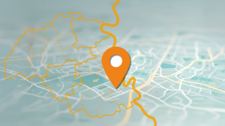 Eine stilisierte Karte mit einem orangefarbenen Standortmarker in der Mitte. Die Karte zeigt ein Straßennetz und eine gelbe, unregelmäßige Umrisslinie, die den IHK-Bezirk Mittlerer Niederrhein darstellt.kiert.