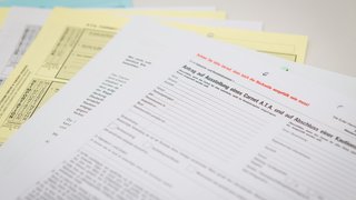 Mehrere übereinanderliegende Formulare in deutscher Sprache, im Vordergrund ein Antrag auf Ausstellung eines Carnet A.T.A., teilweise ausgefüllt und mit Hinweisen in roter Schrift.