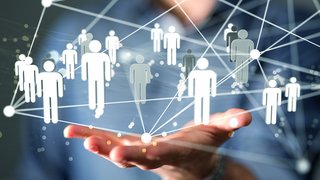 Offene Handfläche einer Person im Anzug, darüber schwebt ein Netzwerk aus verbundenen, stilisierten menschlichen Symbolen, die durch Linien und Punkte verbunden sind. Das Bild symbolisiert soziale Netzwerke, Personalmanagement oder Fachkräftesicherung im digitalen Kontext.