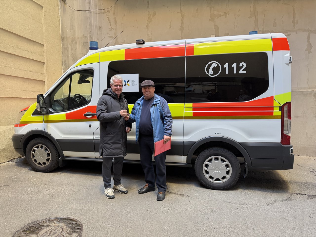 IHK-Hauptgeschäftsführer Jürgen Steinmetz (l.) übergibt ein Rettungsfahrzeug an Volodymyr Resnichenko von der Stadt Marganets im Oblast Dnipropetrowsk.